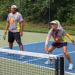 Alameda Post - two pickleball players. One swings at the ball on the court
