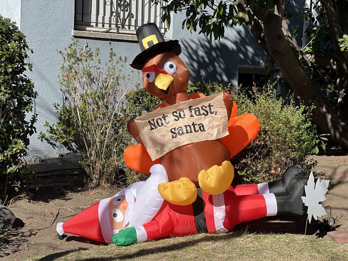 Alameda Post - A blow up decoration on the lawn. It's a turkey sitting on top of Santa. The turkey holds a sign that says "Not so fast, Santa."