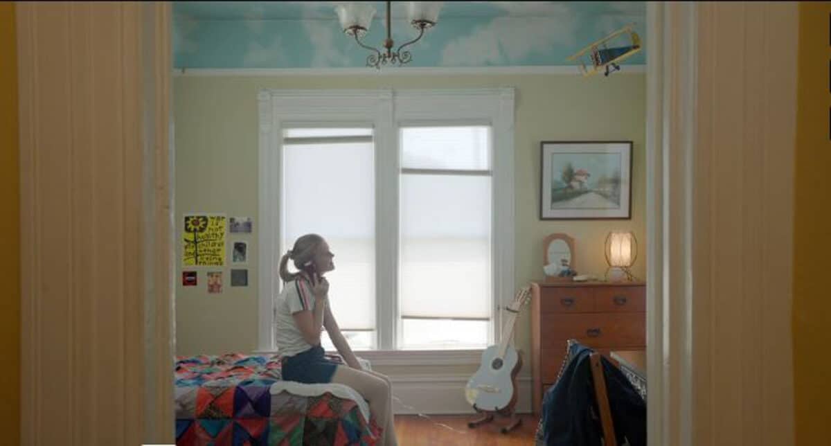 Alameda Post - A girl who appears to be in her teens sits on the bed of a childhood bedroom and talks on the phone. 
