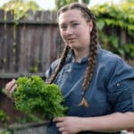 Alameda Post - a photo of Shannon Marsden holding a head of leafy greens outdoors