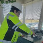 Alameda Post - a man in a high visibility yellow shirt and a hard hat puts his hand on a crank that raises a bridge