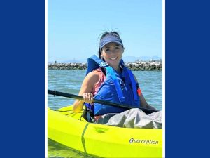 Alameda Post - a woman smiles broadly while sitting in a kayak on the water