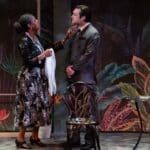 Alameda Post - two actors in Suddenly Last Summer talk onstage a richly decorated set that appears like an outdoor garden