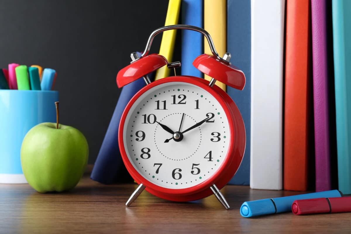 Alameda Post - an alarm clock in front of school supplies on a desk.