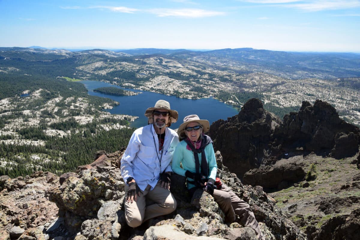 Alameda Post - two people smile for the camera with a scenic view in the background, including a lake