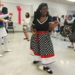 Alameda Post - a woman in a polka dot black, white, and red dress dances amongst the attendees at the Boomer Dance Party