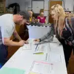 Alameda Post - a man fills out his mail ballot while being assisted by a poll worker